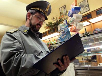 Ein Polizist der italienischen Guardia di Finanza (Finanzpolizei) prüft die Abrechnungen in einer Bar in Pontedera bei Pisa in Italien. Foto: Franco Silvi/Archiv Italienische Finanzpolizei