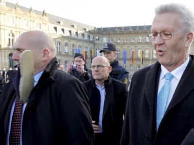 Ein Personenschützer des baden-württembergischen Ministerpräsidenten Winfried Kretschmann (r) wird von einem Schuh getroffen. Foto: Bernd Weißbrod Schuh für Kretschmann