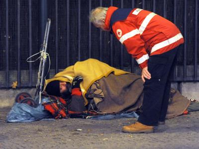 Mitarbeiter der DRK-Kältehilfe kümmern sich in Berlin um einen Obdachlosen, der auf der Straße schlafen will. Foto: Maurizio Gambarini Obdachloser in der Kälte