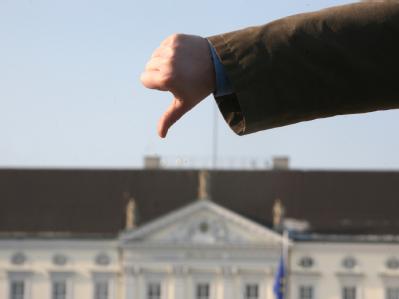 Mit einem nach unten zeigenden Daumen protestiert ein Demonstrant vor dem Schloss Bellevue in Berlin. Foto: Stephanie Pilick Protest gegen Wulff