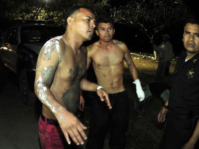 Ein Polizist bewacht zwei Häftlinge, die lebend aus einem brennenden Gefängnis in Honduras entkommen konnten. Foto: Gustavo Amador Gefängnisbrand