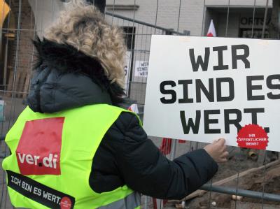 Die Teilnehmerin eines Warnstreiks befestigt vor dem Rathaus in Rostock ein Schild mit einem Verdi-Slogan. Foto: Bernd Wüstneck Warnstreiks im öffentlichen Dienst erreichen Norddeutschland