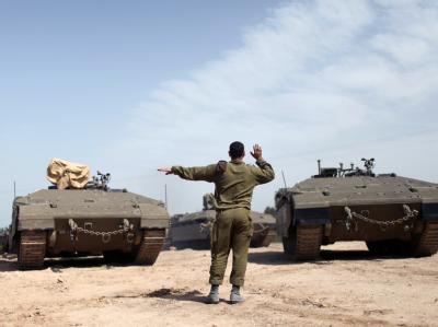 Ein israelischer Soldat dirigiert gepanzerte Fahrzeuge an der Grenze zum Gazastreifen. Foto: Abir Sultan Brüchige Waffenruhe