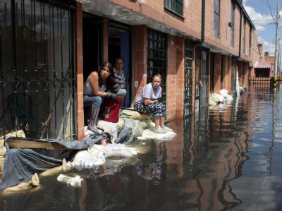 Frauen warten vor ihren teilweise unter Wasser stehenden Häusern im Jahre 2011 in Bogota auf Hilfe. In Kolumbien hatte das Wetterphämonen La Nina für Überschwemmungen gesorgt. Foto: Mauricio Duenas/Archiv Überschwemmung in Kolumbien