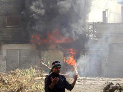 Ein Mann steht vor einem brennenden Gebäude in Homs (Syrien). Foto: LCC Homs