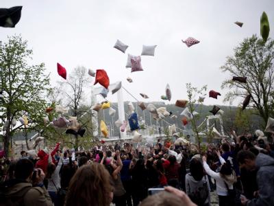 Teilnehmer des «Pillow Fight Day» in Budapest werfen ihre Kissen in die Luft. Foto: Janos Marjai Kissen am Himmel