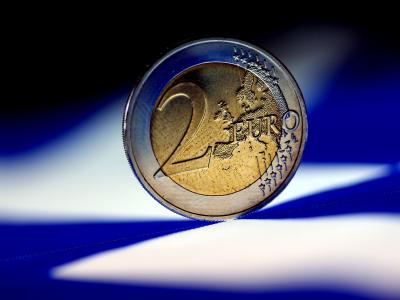 Eine Euro-Münze liegt auf einer griechischen Fahne. Foto: Oliver Berg/Symbolbild Euromünze