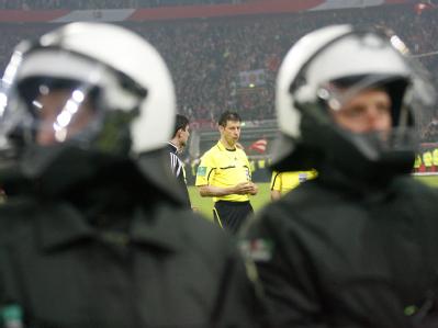 Schiedsrichter Wolfgang Stark (M) holte die Einschätzung der Polizei ein, bevor er das Spiel wieder anpfiff. Foto: Roland Weihrauch Beschützt