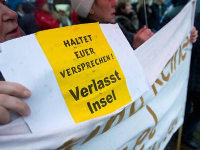 Mit einem Zettel und der Aufschrift «Haltet Euer Versprechen! Verlasst Insel» demonstrieren Bewohner in Insel für den Wegzug von zwei entlassenen Sexualstraftätern. Foto: Jens Wolf/Archiv Demo gegen entlassene Sexualstraftäter
