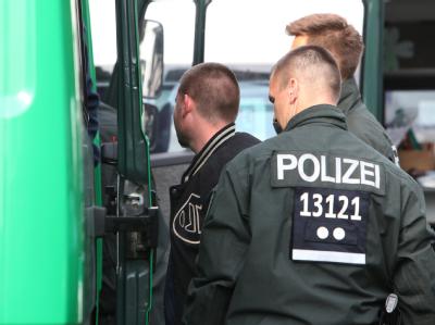 Ein mutmaßliches Mitglied einer Rockerbande wird in Hennigsdorf zur Feststellung der Personalien in ein Polizeifahrzeug geführt. Foto: Nestor Bachmann Polizei- Razzia in Hennigsdorf