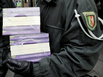 Polizeibeamte tragen Schriften aus der «Millatu Ibrahim Moschee» in Solingen. Foto: Henning Kaiser Razzia gegen Salafisten