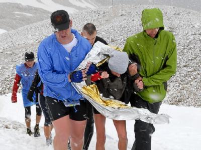 Wettkampfteilnehmer stützen eine völlig erschöpfte und durchgefrorene Läuferin während eines Extrem-Berglaufs auf der Zugspitze (Archivbild). Zugspitz-Lauf