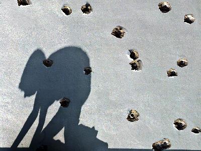 Der Schatten eines palästinensischen Jungen wandert im strahlenden Sonnenschein über eine von Einschusslöchern übersäte Hauswand im Gazastreifen. Archivfoto: Mohammed Saber Hauswand