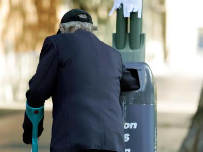 In einem Mülleimer in Berlin sucht ein alter Mann nach Verwertbarem. Foto: Rainer Jensen/Archiv Altersarmut