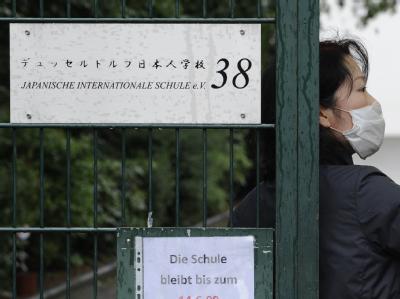 Eine Frau mit Mundschutz am Tor der Schule in Düsseldorf. Schuleingang