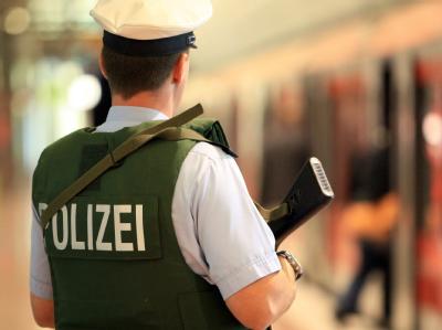 Ein mit einer Maschinenpistole bewaffneter Polizist patrouilliert im S-Bahnhof des Airport Hamburg. Sicherheit auf Bahnhof