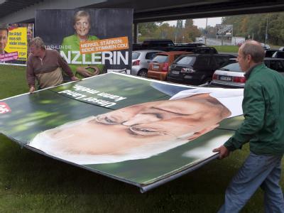 Zwei Arbeiter demontieren ein Wahlplakat mit der Abbildung des SPD-Spitzenkandidaten Frank-Walter Steinmeier in Berlin. Abbau Wahlplakate