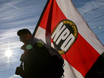 Ein Teilnehmer einer NPD-Demonstration mit einer Fahne der Partei. (Archivbild) NPD-Anhänger