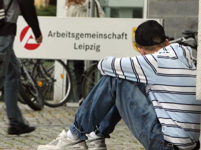 Ein junger Mann sitzt vor dem Eingang zur Agentur für Arbeit in Leipzig. Jugendarbeitslosigkeit