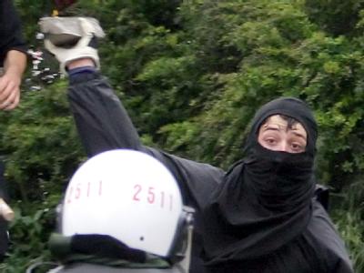 Ein Vermummter wirft während einer Demonstration einen Stein auf einen Polizisten. (Archivfoto). Gewalt gegen Polizisten