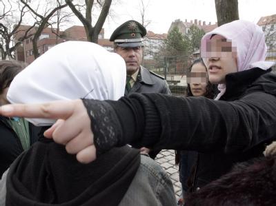Der Polizist Michael Merkle von der Pressestelle der Berliner Polizei unterhält sich vor der Rütli-Hauptschule im Berliner Bezirk Neukölln mit Kopftuch tragenden Schülerinnen (Archivfoto vom 31.3.2006). Rütli-Hauptschule