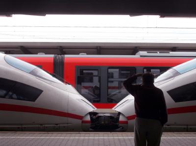Ein Reisender blickt auf dem Augsburger Hauptbahnhof auf einen stehenden ICE und einen Regionalzug. (Archivbild) ICE