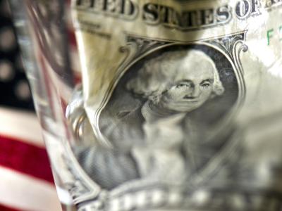 Durch ein Wasserglas verzerrt: Dollar-Banknote. Foto: Arno Burgi Dollar