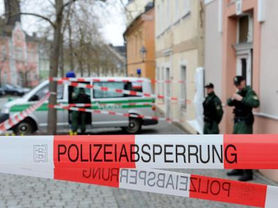 Zwei Polizisten bewachen im April im bayerischen Lichtenberg einen Hauseingang. Foto: David Ebener Polizeiabsperrung