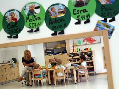 Kinder, die ihr Mittagessen einnehmen, spiegeln sich in einer städtischen Kindertagesstätte. Foto: Oliver Berg/Archiv Kindertagesstätte