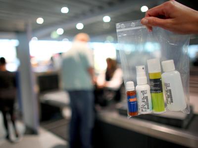 Eine Mitarbeiterin der Bundespolizei hält auf dem Flughafen Köln-Bonn an der Flugsteigkontrolle einen Beutel mit Fläschchen hoch. Foto: Oliver Berg/Symbolbild Flüssigkeiten an Bord
