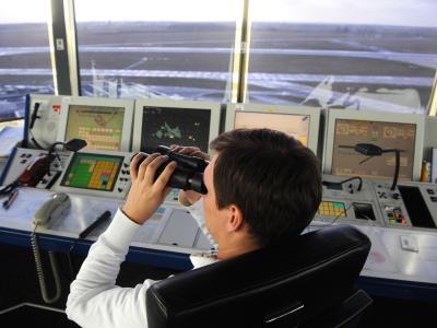 Ein Fluglotse auf dem Tower am Flughafen in Bremen schaut mit einem Fernglas über das Vorfeld des Airports. Foto: Ingo Wagner Tower am Bremer Flughafen