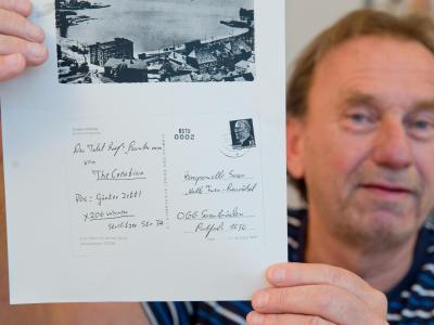 Günter Zettl mit einem Blatt Papier aus seiner Stasi-Akte, auf dem die Kopie der von ihm 1969 versandten Postkarte zu sehen ist. Foto: Daniel Karman Postkarten-Kopie