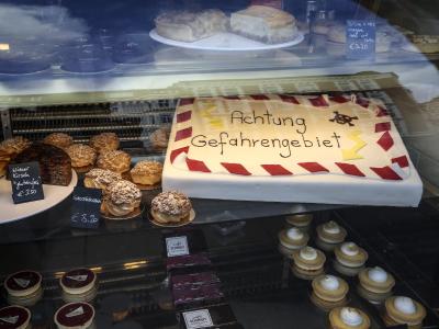 Ein Kuchen mit der Aufschrift «Achtung Gefahrengebiet» liegt im Schaufenster eines Hamburger Cafés. Foto: Axel Heimken Humorvoller Umgang