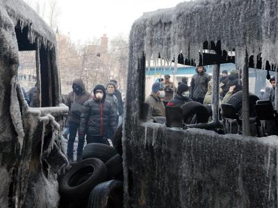 Demonstranten stehen in Kiew hinter den Wracks ausgebrannter Polizeibusse. Foto: Sergej Dolzhenko Demonstranten