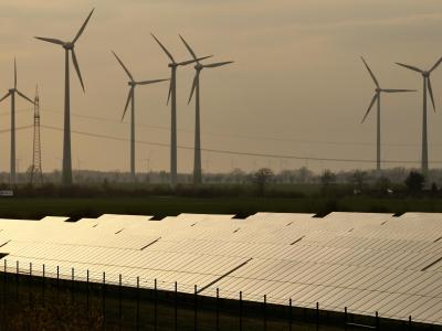 Deutschland pocht auf ein Pflichtziel für Strom aus Sonne oder Wind - auch, weil die Bundesregierung sich Unterstützung für die deutsche Energiewende erhofft. Foto: Jan Woitas Windräder hinter Solarpark