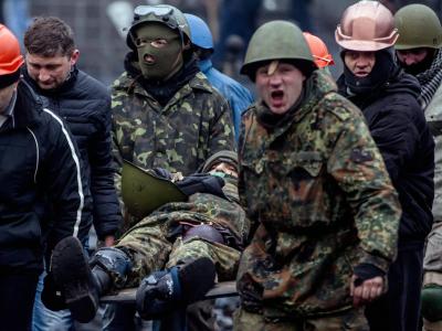 Polizisten bringen einen verletzten Kollegen in Sicherheit. Foto: Yevgeny Maloletka Polizisten