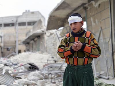 Das am 25.02.2014 veröffentlichte Foto zeigt einen verletzten Jungen, der nach einem Bombenangriff im syrischen Aleppo vor dem zerstörten Haus seiner Familie steht. Mindestens die Hälfte der vom Krieg vertriebenen Syrer sind nach UN-Angaben Kinder. Foto: Bürgerkrieg in Syrien
