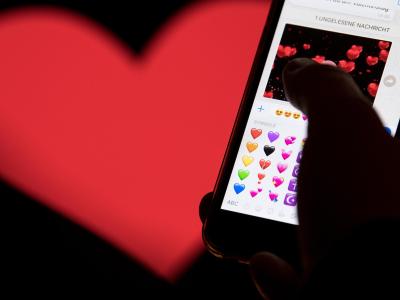 Smartphone mit Emojis aus WhatsApp vor dem WhatsApp-Logo. Foto: Fabian Sommer Chatten zum Valentinstag