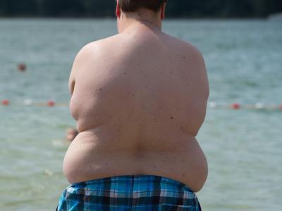 Ein fettleibiger Junge steht an einem Badesee. 26,3 Prozent der Fünf- bis Siebzehnjährigen in Deutschland Übergewicht, 8,8 Prozent sind von Adipositas und damit von extremen Übergewicht betroffen. Zu dick