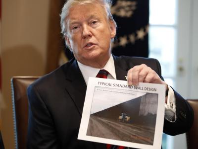 Donald Trump hält ein Foto einer möglichen Grenzmauer in der Hand. Donald Trump