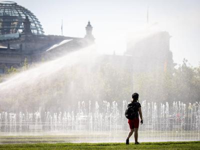 Eine Passantin erfrischt sich in einer Wasserfontäne vor dem Reichstag in Berlin. Nicht nur die Hauptstadt schwitzt. Hitze in Deutschland
