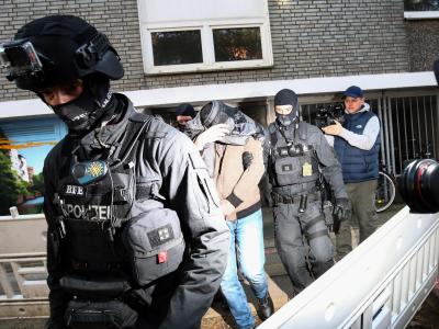 Terror-Razzia in Hamburg: Ein Mann wird von Polizisten aus einem Haus geführt. Razzia
