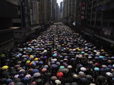 Tausende Hongkonger ziehen mit Regenschirmen über eine Straße. Proteste in Hongkong