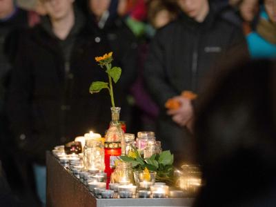 Trauernde stehen auf dem Marktplatz in Halle hinter brennenden Kerzen. Trauer nach Schüssen in Halle