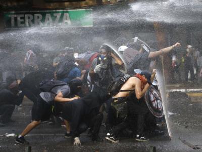 Demonstranten schützten sich in Santiago de Chile vor einem Wasserwerfer. Proteste in Chile