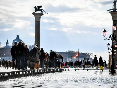 Touristen gehen über Stege, die über das Hochwasser führen. Trockenen Fußes