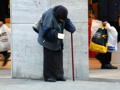In der Kölner Innenstadt bittet eine alte Frau um Almosen. Bitte um Almosen