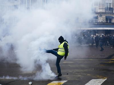 Ein Demonstrant tritt einen Tränengasbehälter von sich weg. Tränengas in Paris
