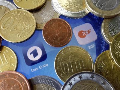 Euromünzen liegen neben den Logos der Apps von ARD und ZDF. Rundfunkbeitrag