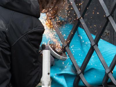 Mitarbeiter einer Restaurierungsfirma arbeiten mit einem Winkelschleifer am durchtrennten Gitterfenster des Grünen Gewölbes. Fenster